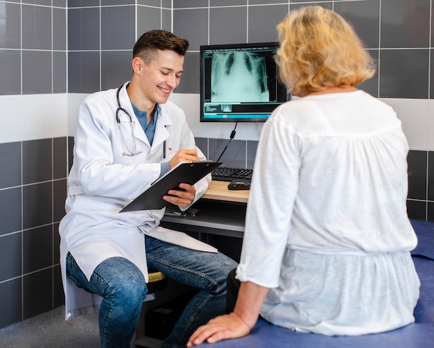 Kostenloses Foto doktor und patient, die über eine röntgenaufnahme sprechen