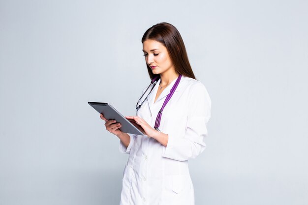 Doktor unter Verwendung eines Tablet-Computers isoliert über einer weißen Wand