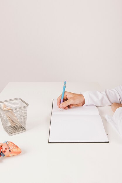 Doktors Hand schreibt auf seinem Notizbuch