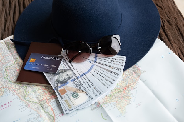 Dollarbanknoten, Sonnenbrille, Kreditkarte, Pass und blauer Hut