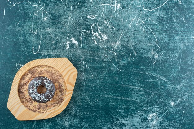 Donut auf einer Holzplatte, auf blauem Hintergrund. Foto in hoher Qualität