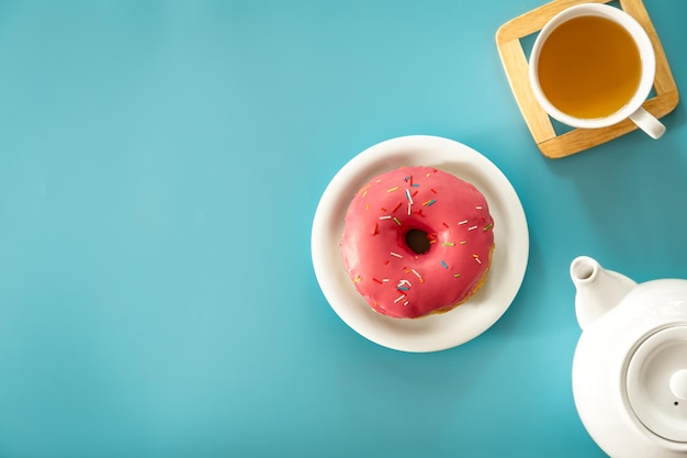 Donut und Tee auf blauem Hintergrund liegen flach