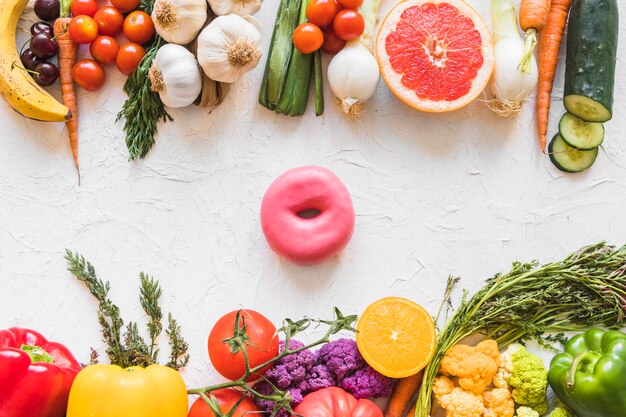 Donut zwischen dem bunten gesunden und ungesunden Lebensmittel auf weißem strukturiertem Hintergrund