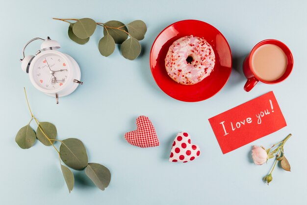 Donutfrühstück mit der Anmerkung des Valentinsgrußes und Dekorationen