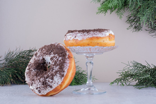 Donuts, die gegen einen Glashalter auf weißem Hintergrund lehnen.