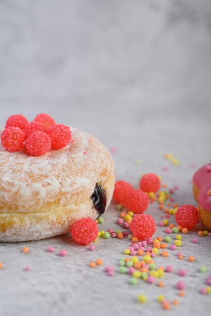 Donuts mit Puderzucker und Süßigkeiten auf einer weißen Oberfläche bestreut.