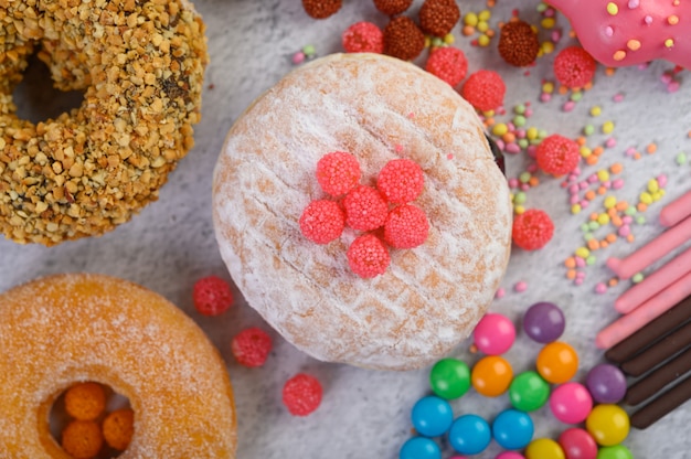 Donuts mit Puderzucker und Süßigkeiten auf einer weißen Oberfläche bestreut.