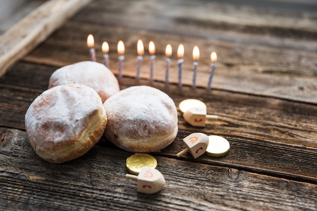 Donuts und Chanukka-Symbole in der Nähe von Kerzen