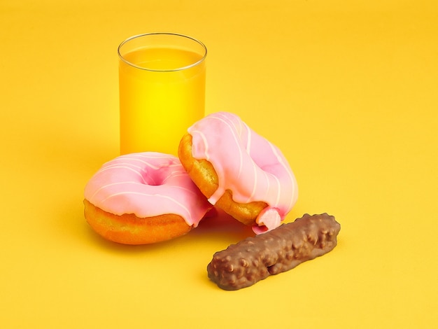 Kostenloses Foto donuts und frischer orangensaft auf gelb