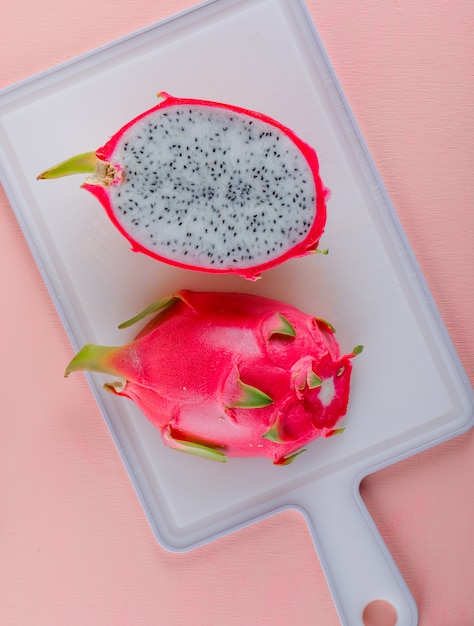 Kostenloses Foto drachenfrucht auf rosa und schneidebrett. draufsicht.