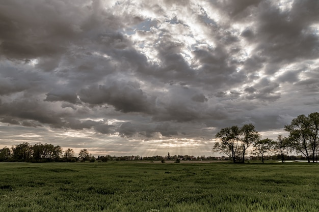 Kostenloses Foto dramatische landschaftsansicht mit sonnenstrahlen, die durch einen dunklen bewölkten himmel scheinen