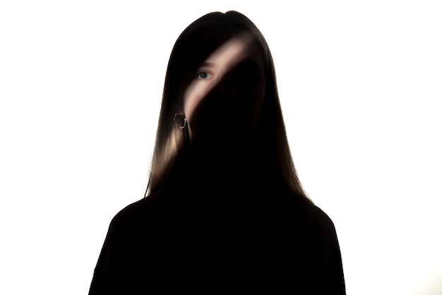 Dramatisches Porträt des jungen Mädchens in der Dunkelheit lokalisiert auf weißer Studiowand