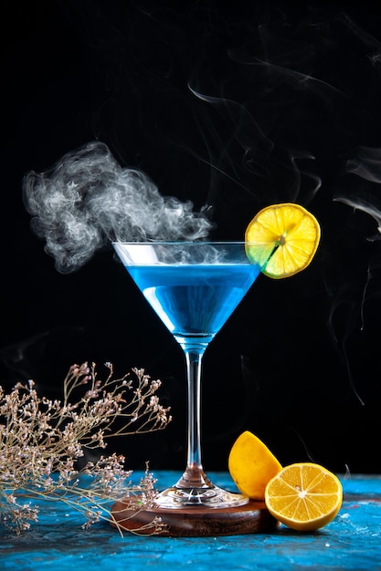Draufsicht auf Alchocol-Cocktail in einem Glasbecher, serviert mit Zitronenscheibe und Tannenzweigen auf blauem Tisch