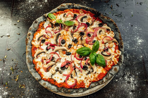 Draufsicht auf appetitliche Pizza mit schwarzem Teig und verschiedenem Gemüse