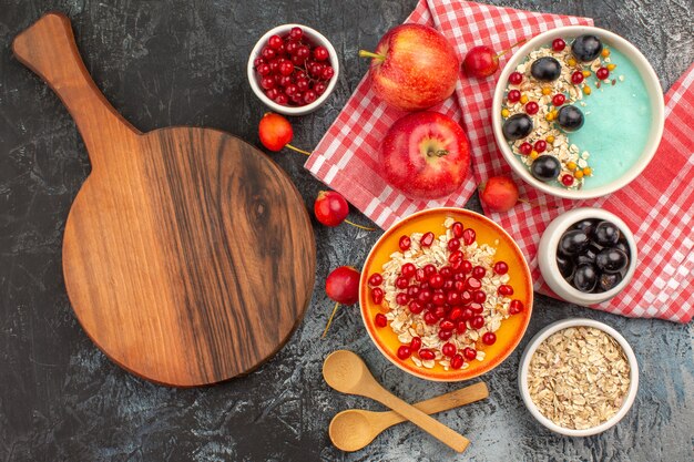 Draufsicht auf Beerenlöffel Äpfel bunte Beeren Haferflocken Granatapfel das Schneidebrett