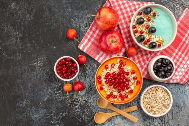 Draufsicht auf Beerenlöffel rote Johannisbeeren Kirschen Trauben Äpfel Granatapfel Haferflocken in Schüssel