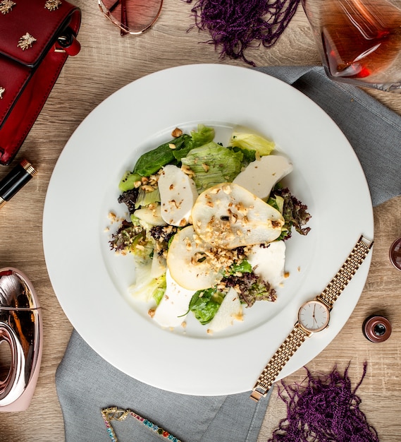 Draufsicht auf Birnensalat mit Salatkäse-Kiwi und Walnüssen