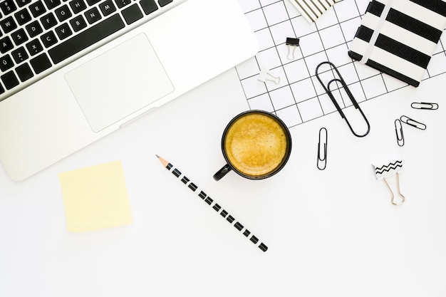 Draufsicht auf Büromaterial mit Kaffee und Laptop