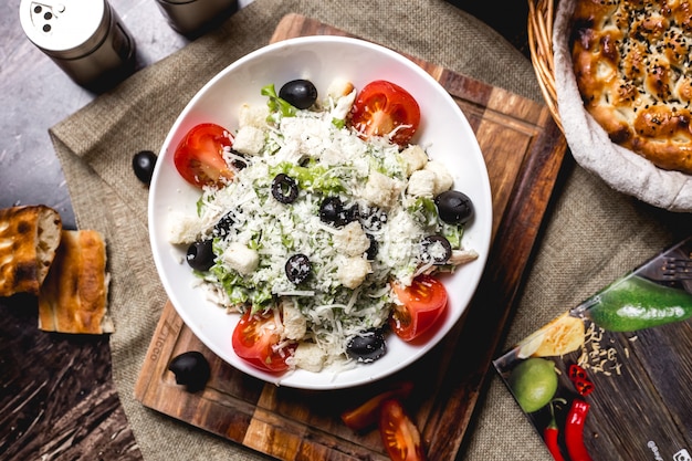 Draufsicht auf Caesar Salatschüssel, garniert mit geriebenem Käse und Oliven