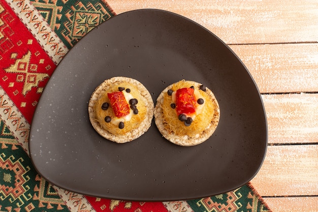 Draufsicht auf Cracker und Kuchen innerhalb der braunen Platte