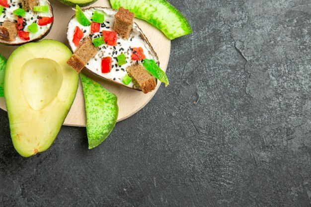 Draufsicht auf cremige Avocados mit Brot und Pfeffer und frischen Avocados auf der grauen Oberfläche
