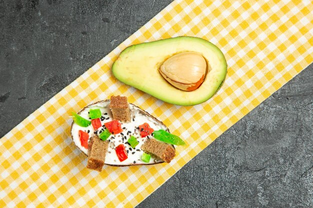 Draufsicht auf cremige Avocados mit frischer Avocado auf dunkelgrauer Oberfläche