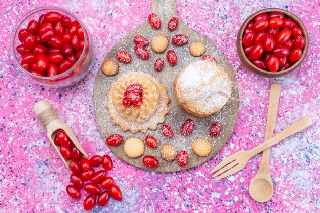 Draufsicht auf cremige Sandwichkekse, die mit roten frischen Hartriegeln auf hellen sauren Fruchtbeeren des Kekskuchenkeks köstlich schmecken