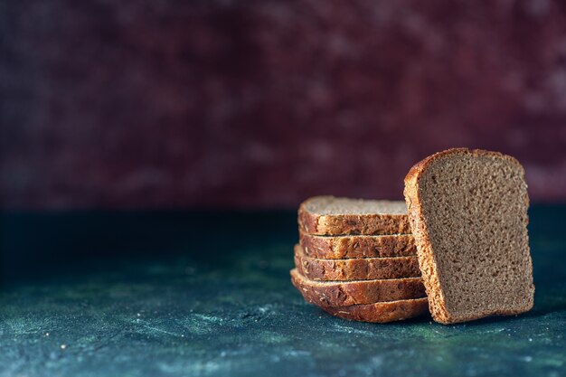 Draufsicht auf diätetische Schwarzbrotscheiben auf der linken Seite auf gemischtem Hintergrund mit freiem Platz