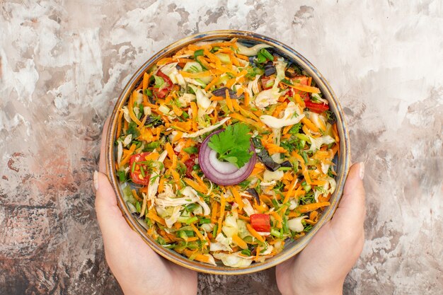 Draufsicht auf die Hände, die frischen leckeren veganen Salat mit verschiedenem Bio-Gemüse halten