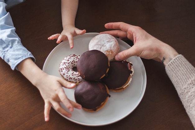 Draufsicht auf die Hände neben einigen Donuts