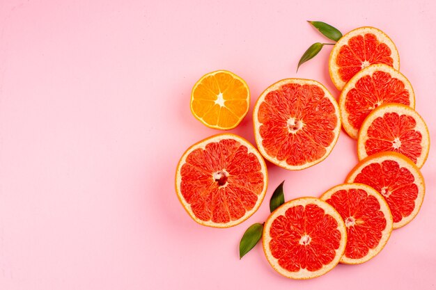 Draufsicht auf die saftigen Fruchtscheiben der leckeren Grapefruits auf der rosa Oberfläche