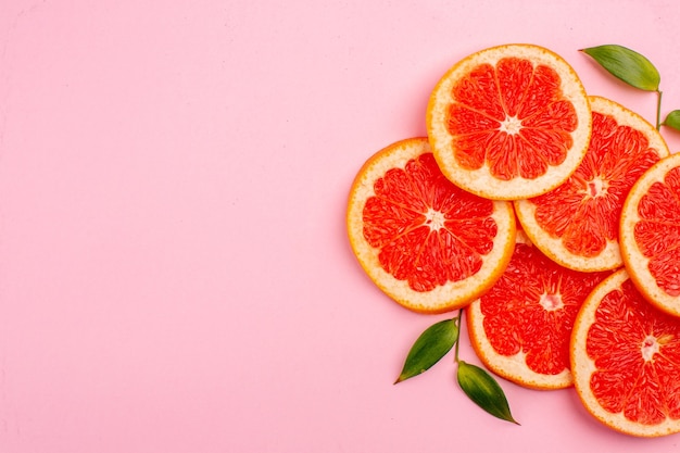 Draufsicht auf die saftigen Fruchtscheiben der leckeren Grapefruits auf der rosa Oberfläche