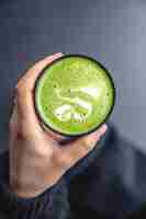 Kostenloses Foto draufsicht auf eine frau, die ein trendiges grünes matcha-getränk mit latte art in den händen hält