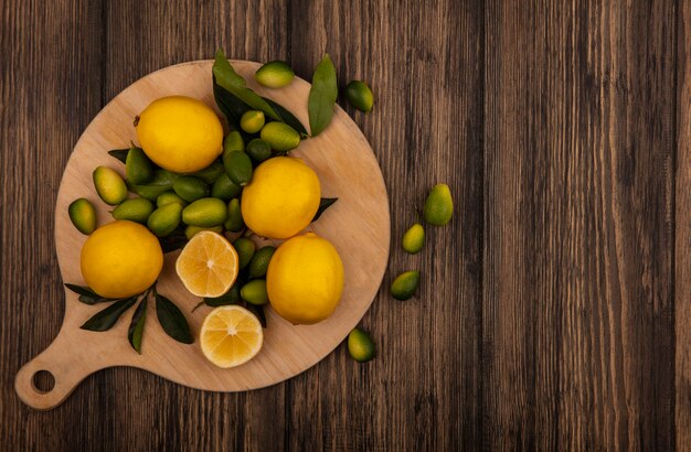 Draufsicht auf eine gute Quelle von Vitamin-C-Zitronen, die auf einem hölzernen Küchenbrett auf einer hölzernen Oberfläche mit Kopierraum isoliert werden