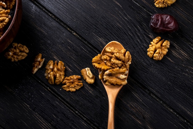 Draufsicht auf einen Holzlöffel mit Walnüssen und süßen getrockneten Dattelfrüchten auf Holz