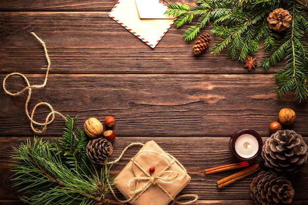 Draufsicht auf einen Holztisch, der mit Kiefernzweigen und Kerzen für Weihnachten verziert wird