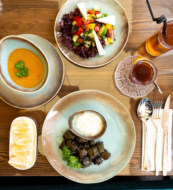 Draufsicht auf einen Tisch, der zum Abendessen mit Dolma-Sturz-Suppe und Gemüsesald serviert wird