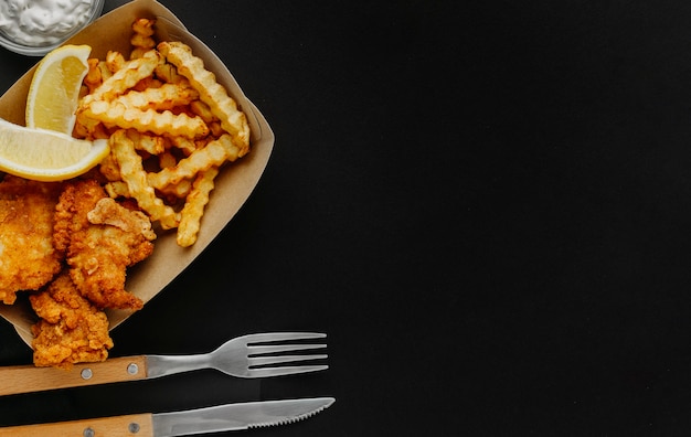 Draufsicht auf Fisch und Chips mit Soße und Besteck