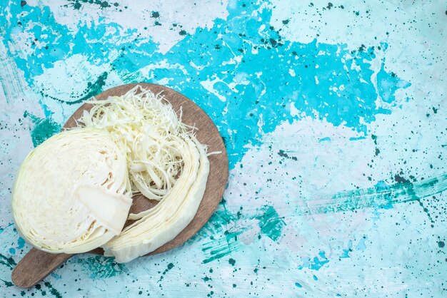 Draufsicht auf frisch geschnittenen Kohl, der auf hellblauem Gemüsesalat mit gesundem Gemüsesnack zusammengesetzt und halb ganz ist