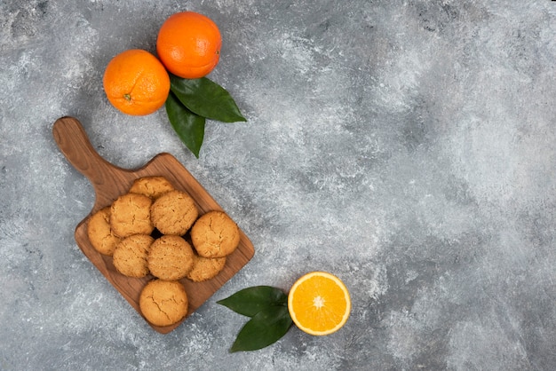 Draufsicht auf frische Bio-Orangen ganz oder geschnitten und hausgemachte Kekse.