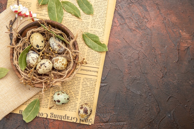 Draufsicht auf frische Eier vom Bauernhof in einem Holztopf verlässt auf einer alten Zeitung auf der rechten Seite auf braunem Hintergrund