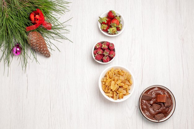 Draufsicht auf frische Früchte mit Rosinen und Schokoladendessert auf weißem Tisch