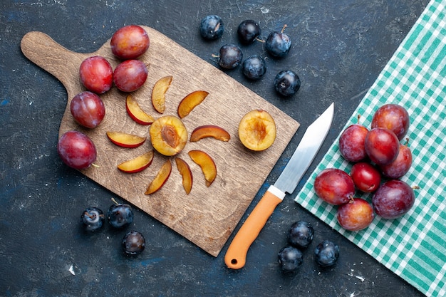 Draufsicht auf frische Pflaumen ganz weich und saftig geschnitten auf grau-dunklem Schreibtisch, fruchtfrischer Vitaminsommer