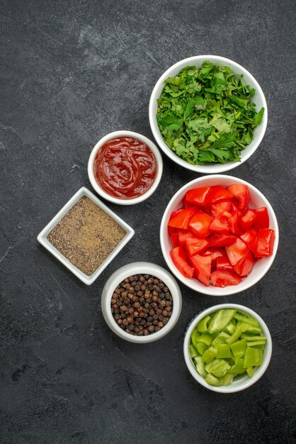 Draufsicht auf frische rote Tomaten in Scheiben geschnittenes Gemüse mit Grüns auf Schwarz