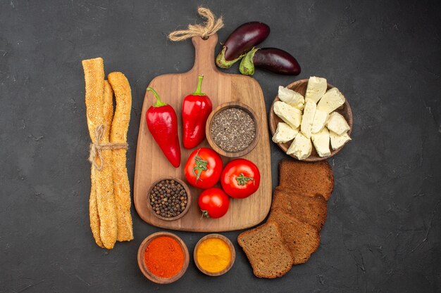 Draufsicht auf frische rote Tomaten mit Gewürzen Käse und Brot auf Schwarz