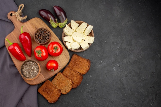 Draufsicht auf frische Tomaten mit Dunkelheit. Brotlaibe und Weißkäse auf Schwarz