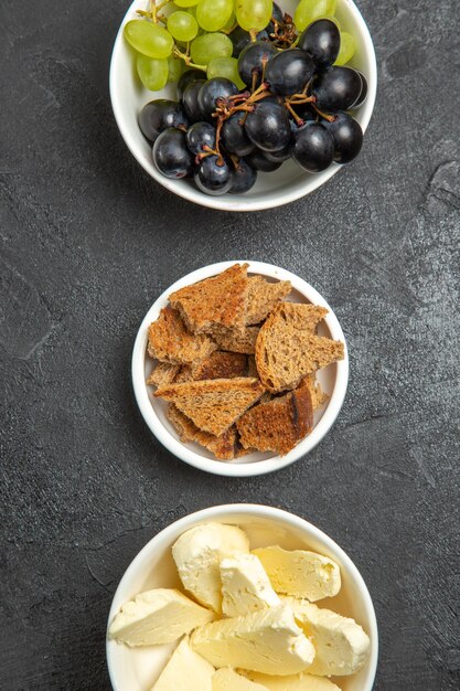 Draufsicht auf frische, weiche Trauben mit Brot und Käse auf dunkler Oberfläche