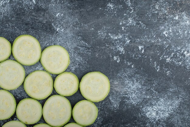 Draufsicht auf frische Zucchinischeiben auf grauem Hintergrund.