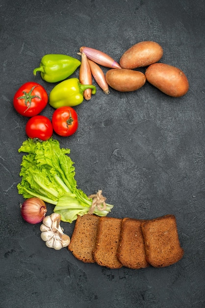 Draufsicht auf frisches gemüse mit schwarzbrotlaiben auf grauem reifem brotsalat gesundheit salad