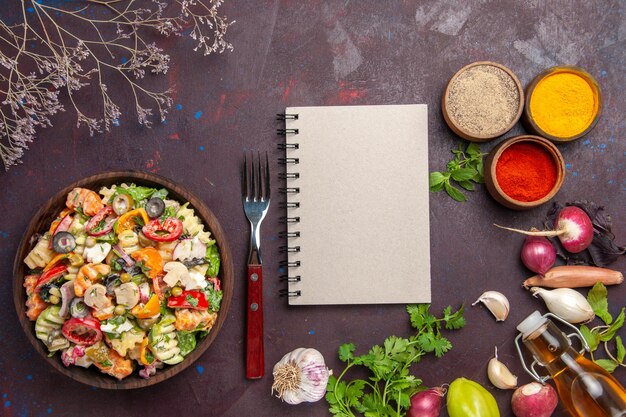 Draufsicht auf frisches Gemüse. Salat mit verschiedenen Gewürzen auf Schwarz